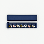 Navy 7-day pill organizer with seven Monday through Sunday compartments shown open