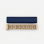 Navy and cream 7-day pill organizer with tray separated and Monday through Sunday compartments visible