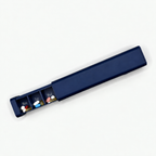 Navy 7-day pill organizer partially open with Monday through Wednesday compartments visible